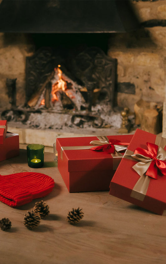 Christmas gift boxes and gifts laid on table infront of log fire