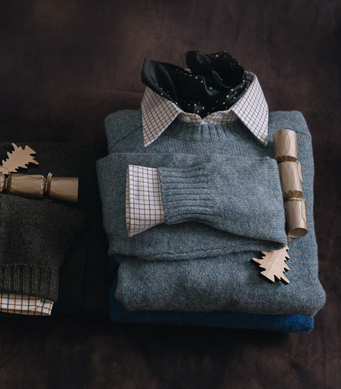 Stack of folded sweaters with decorative items on a dark background