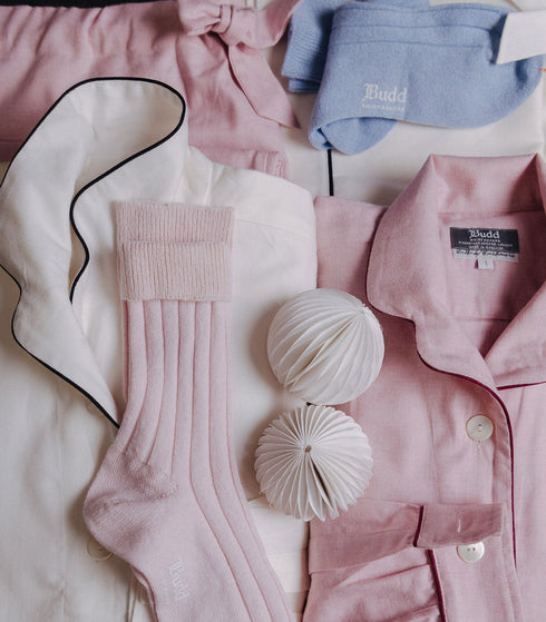 Pink shirt, white socks, blue sleep mask, and decorative items on a light background