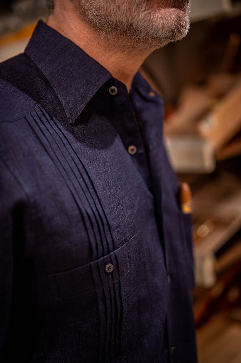Close-up of a person wearing a dark blue shirt with pleated details in a cigar store