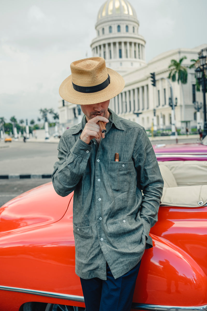 Man in Havana street stood against red vintage car