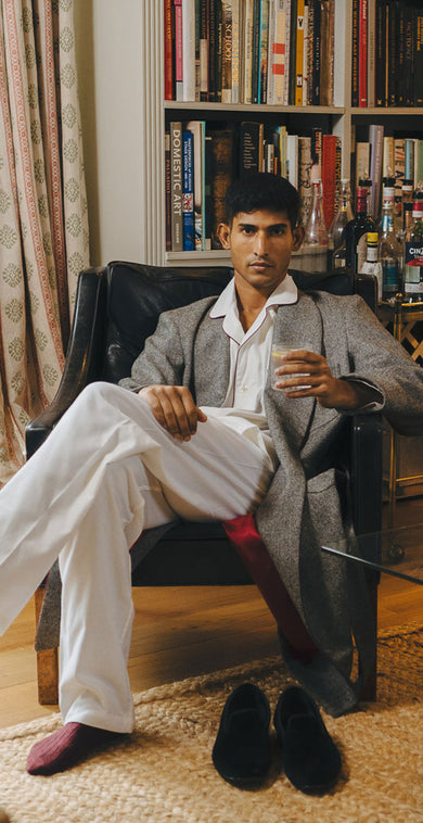 Man sitting in a living room wearing dressing gown with books and decor