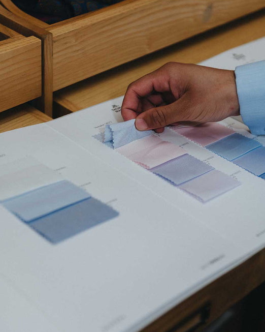 Person holding a color swatch book with a wooden desk in the background