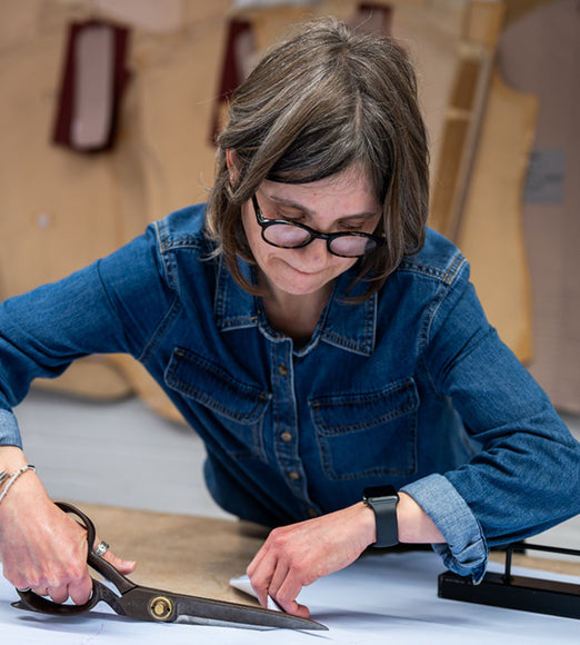 Made to measure cutter in the workroom cutting a shirt pattern