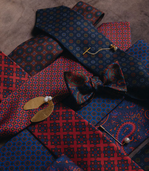 Paisley madder silk items laid across each other with gold mistletoe 