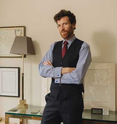 Man in formal attire standing in a room with decor elements.