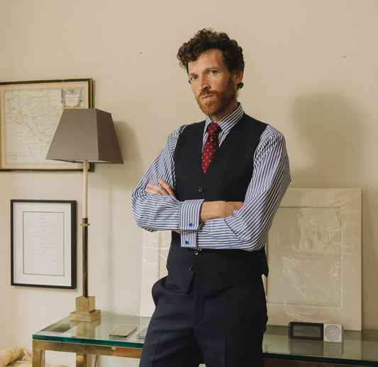 Man in formal attire standing in a room with decor elements.