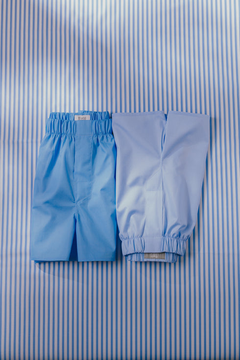 Two pairs of blue boxer shorts on blue stripe background