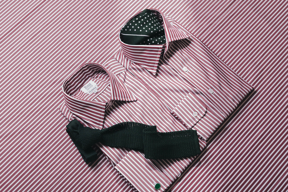 Burgundy stripe shirts laid out on matching fabric background