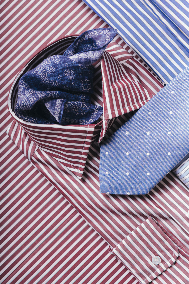 Red and white striped shirt with blue patterned pocket square and blue tie.