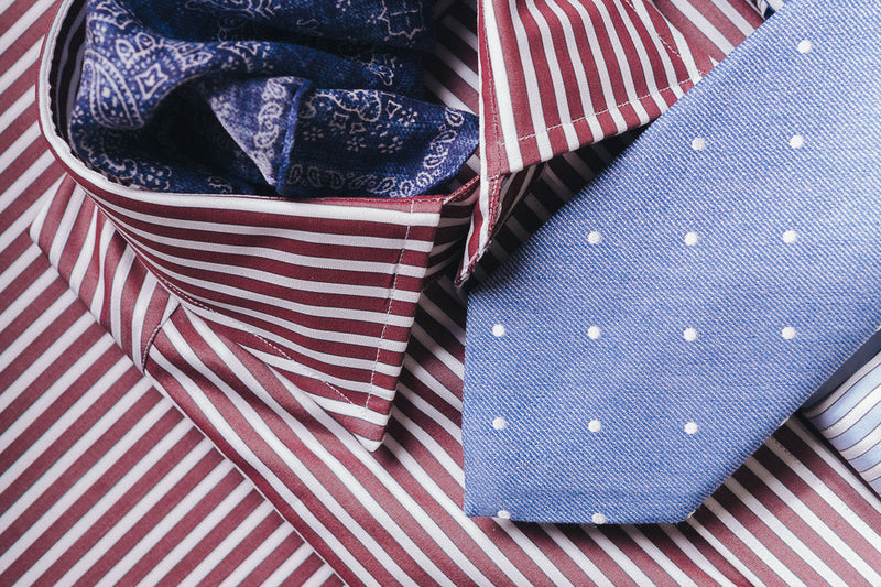 Burgundy stripe shirts laid out on matching fabric background