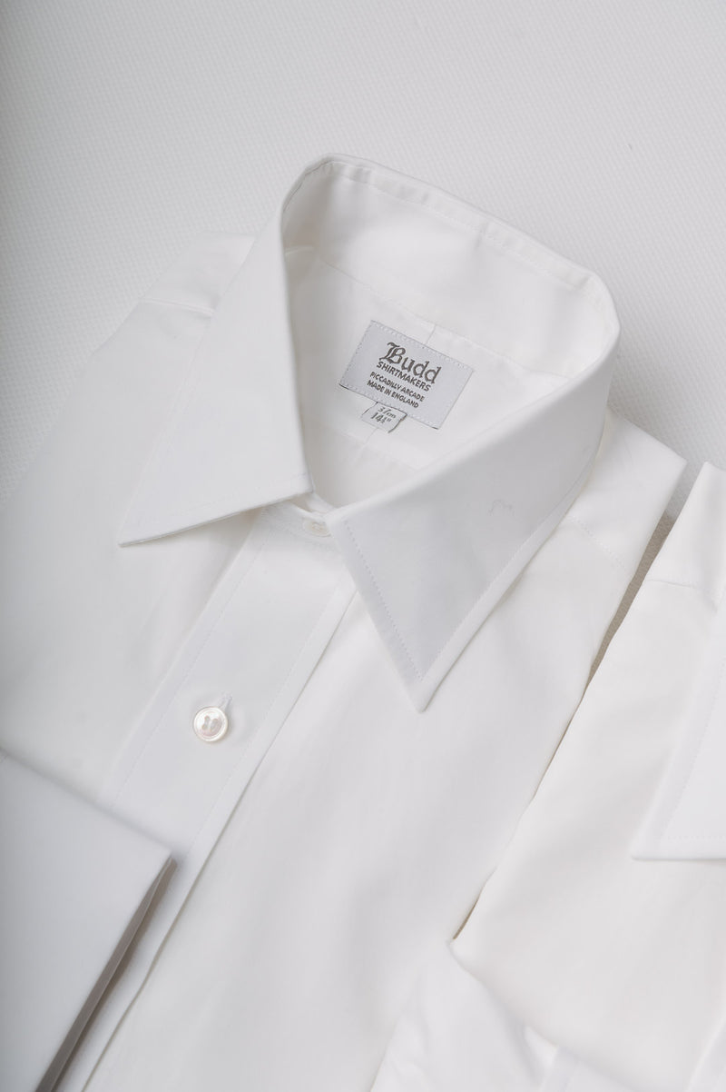 Close-up of a white dress shirt with a collar and label on a light gray background