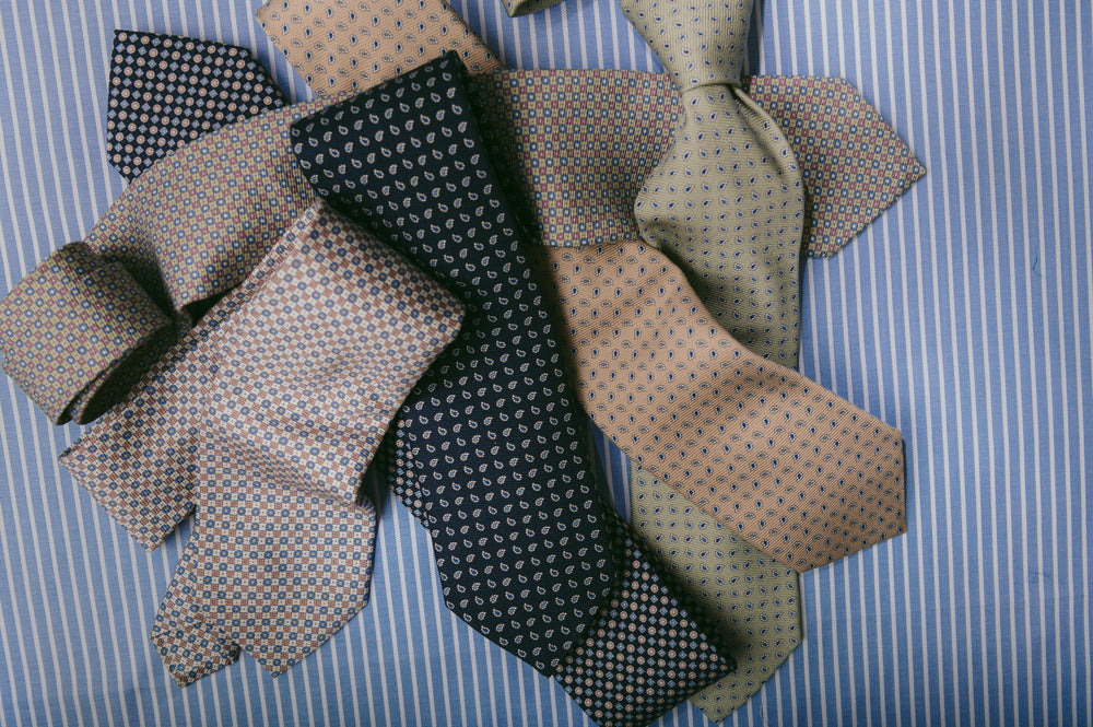 Selection of overlapping ties laid on blue stripe background