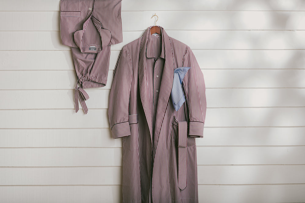 Striped robe and pajama set hanging on a wooden wall.