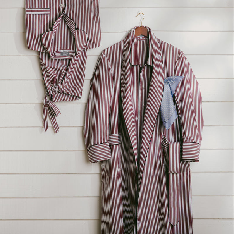 Striped robe and pajama set hanging on a wooden wall.
