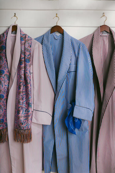 Three stripe dressing gowns hung up against white washed wooden wall