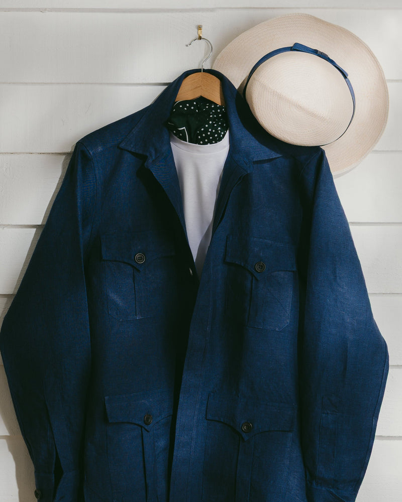 Blue safari linen blazer on a hanger against a white wooden panel background