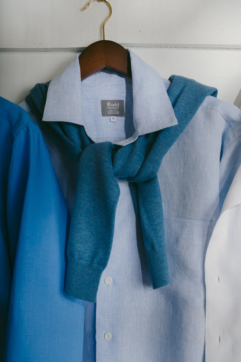 Blue shirt with a matching scarf on a hanger against a white wall