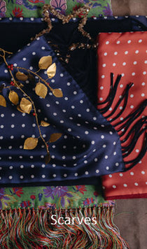 Two scarves, one with white polka dots on a dark blue background and the other with a red background and black design, displayed together.