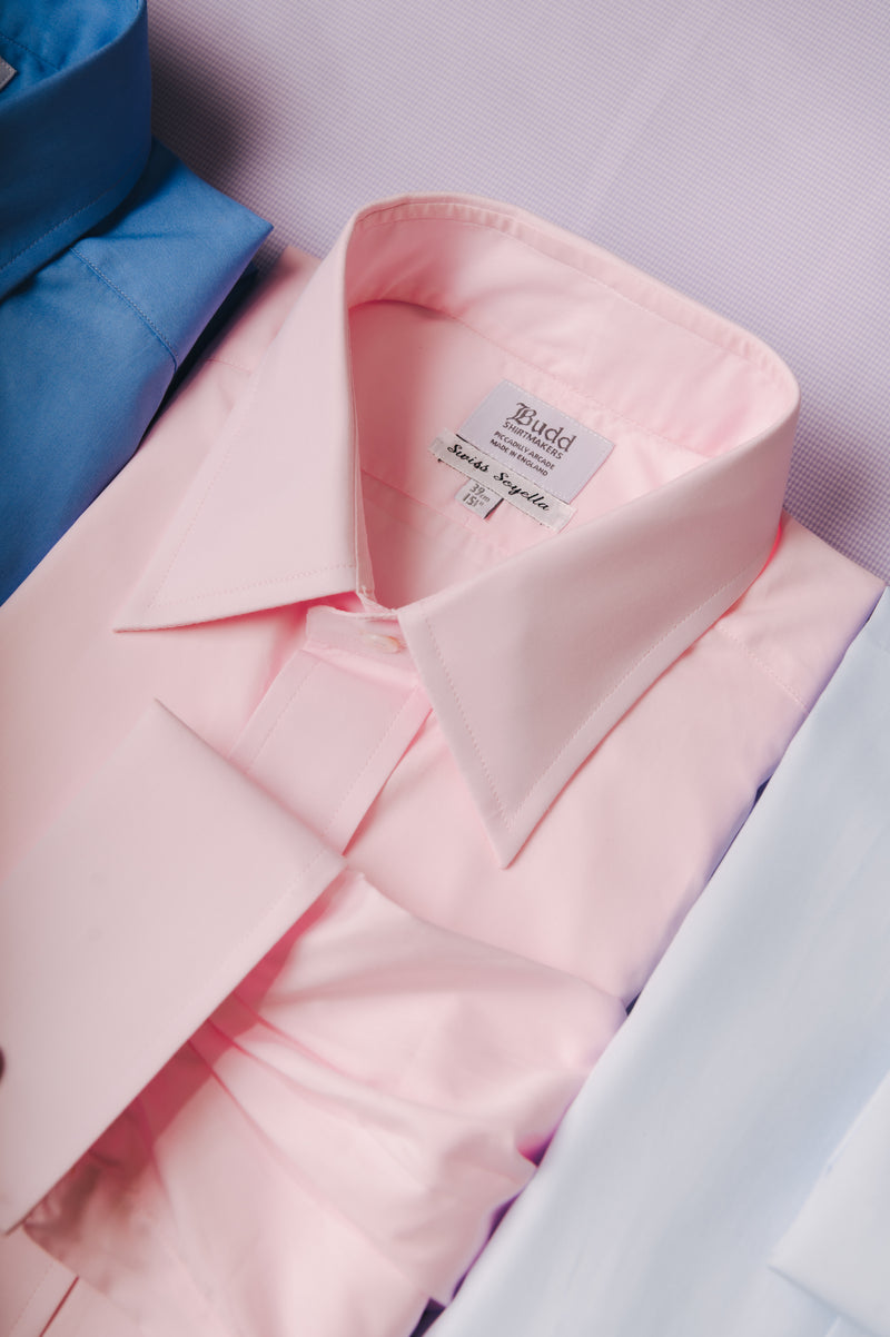 Close-up of a pink dress shirt with a brand label, surrounded by other shirts.
