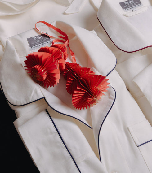 White pyjamas with red decorative elements and visible brand label on a white background