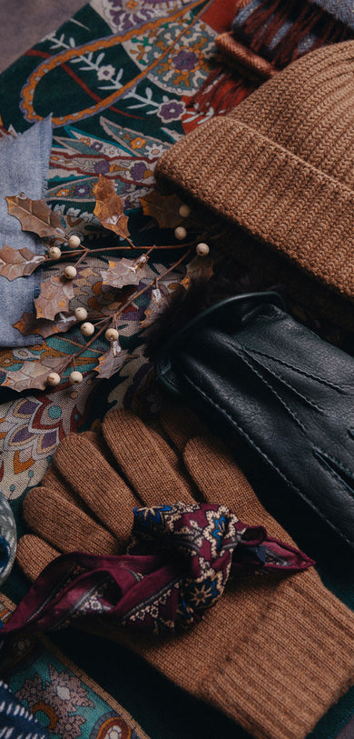 Pair of gloves and hat with a decorative pocket square on a textured surface
