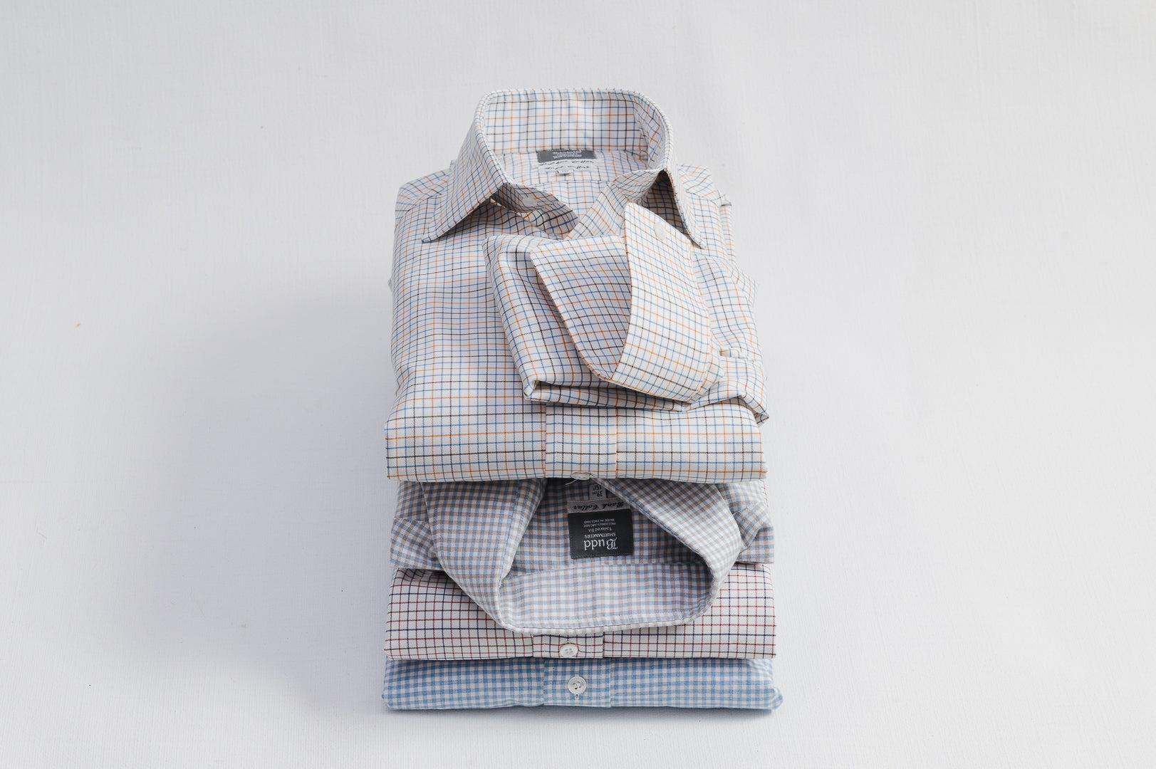 Stack of folded mens shirts with different patterns on a light gray background