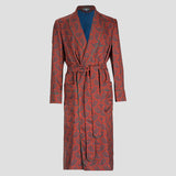 A long-sleeved dressing gown robe with a red and blue paisley pattern, featuring a matching tie belt and a solid blue inner lining, displayed on a neutral gray background.